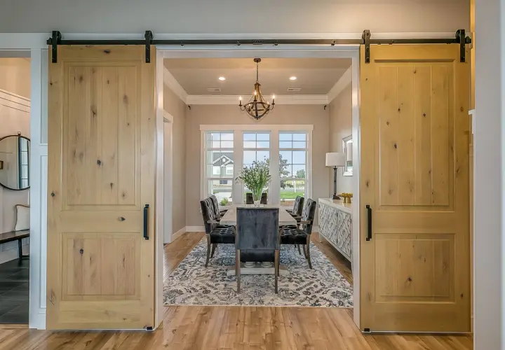 Dos puertas corredizas de madera rústica flanquean un comedor elegante, mostrando diferentes tipos de puertas.