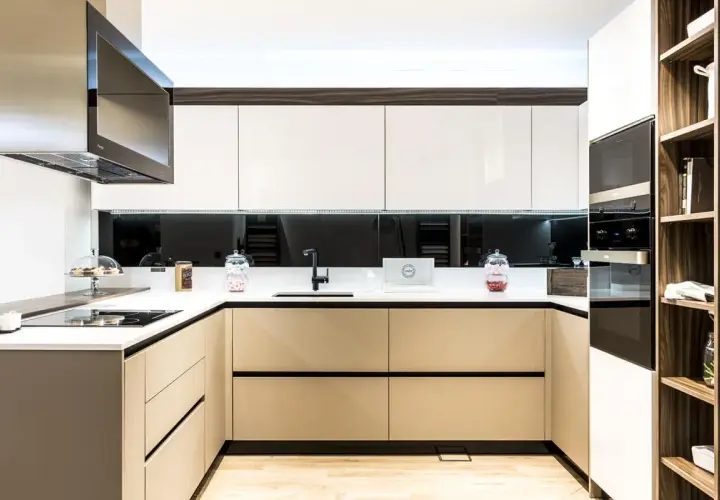 Cocina moderna con gabinetes blancos y beige, encimera blanca, campana extractora de acero inoxidable. Ideas para como diseñar una cocina funcional y elegante.