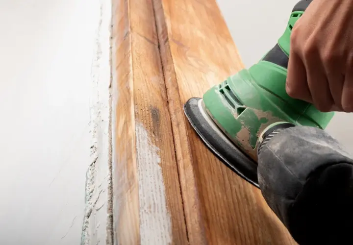 Mano lijando madera para quitar barniz. El proceso revela la veta natural.