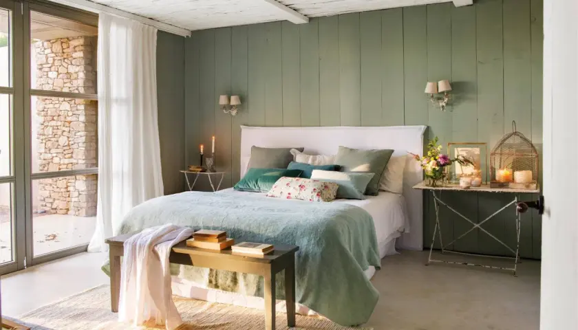 Habitación con paredes verde menta, cama con ropa de cama azul claro y cojines verdes. Inspiración de colores para habitaciones.