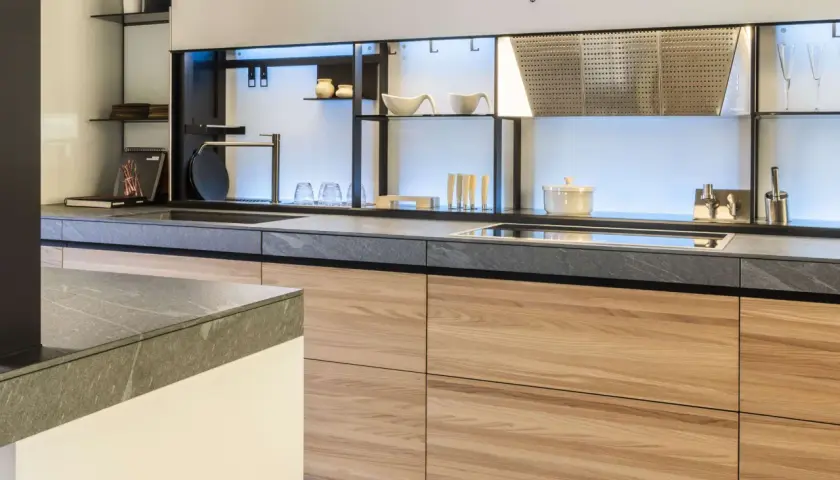 Encimeras resistentes al calor de piedra gris y gabinetes de madera clara en una cocina moderna.