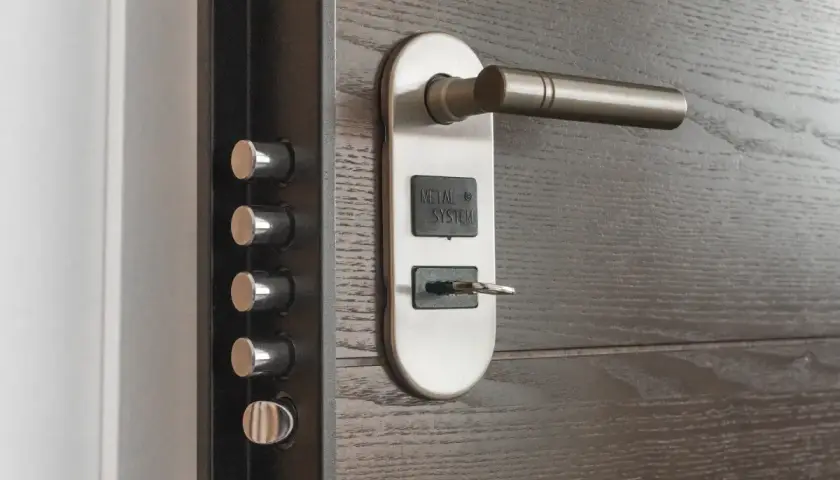 Detalle de una puerta de seguridad con múltiples cerrojos y un cilindro con llave, mostrando varios tipos de cerraduras para protección.