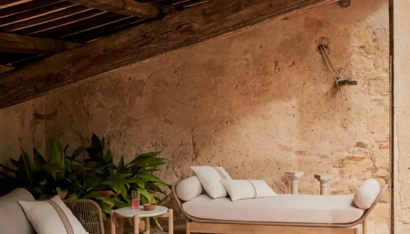 Un rincón acogedor para aprovechar buhardilla muy baja. Sofá, plantas y detalles rústicos bajo vigas de madera.