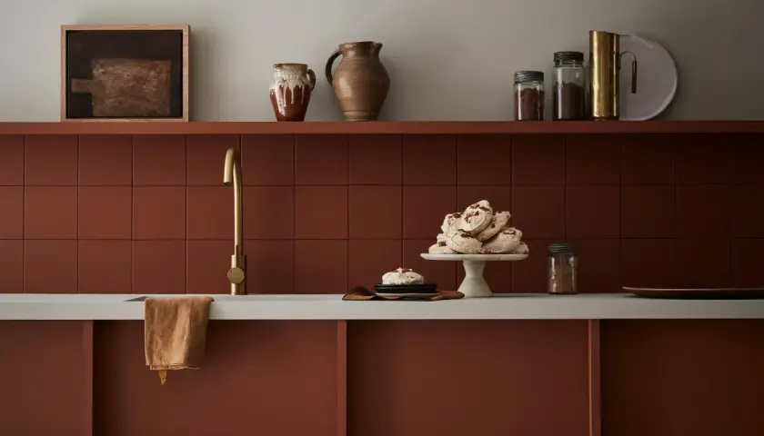 Encimera de cocina pintada en tono terracota, con grifería dorada y detalles decorativos.