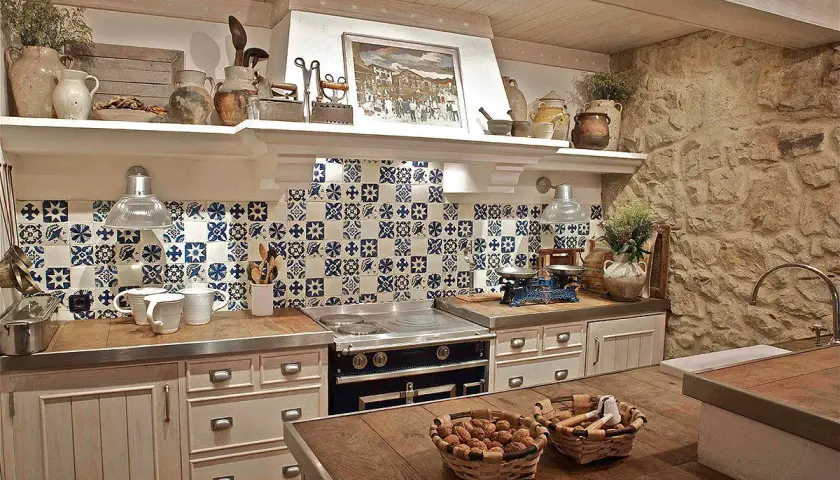 Encantadora cocina rústica con azulejos azules y blancos, encimeras de madera y piedra. Ideal para preparar deliciosas comidas.