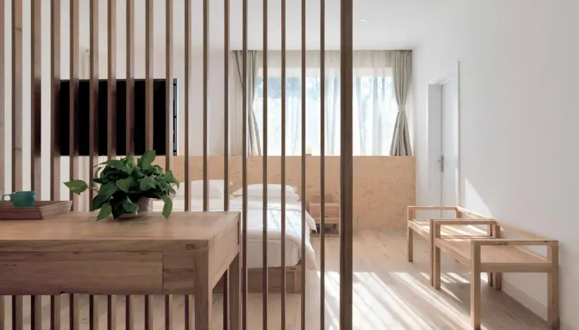 Elegante solución para separar ambientes sin obras, con un biombo de lamas de madera que delimita un dormitorio acogedor.