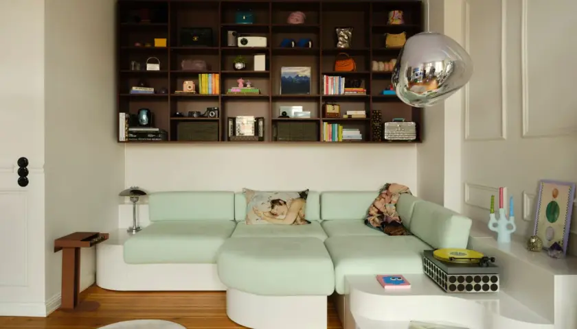 Estantería repleta de objetos y un sofá modular verde menta, demostrando cómo aprovechar espacios pequeños con estilo y funcionalidad.