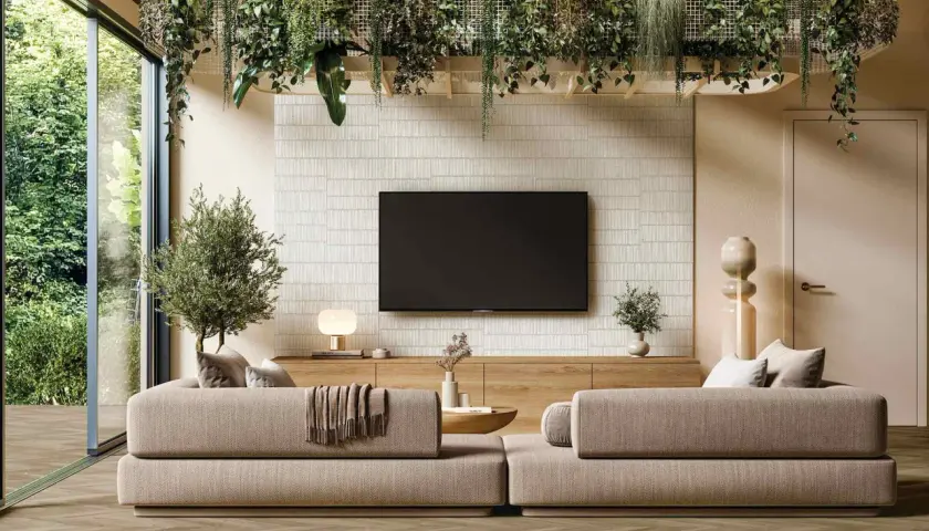 Un salón moderno con sofás beige, una pared con textura y plantas colgantes, reflejando las últimas tendencias en decoración de paredes.