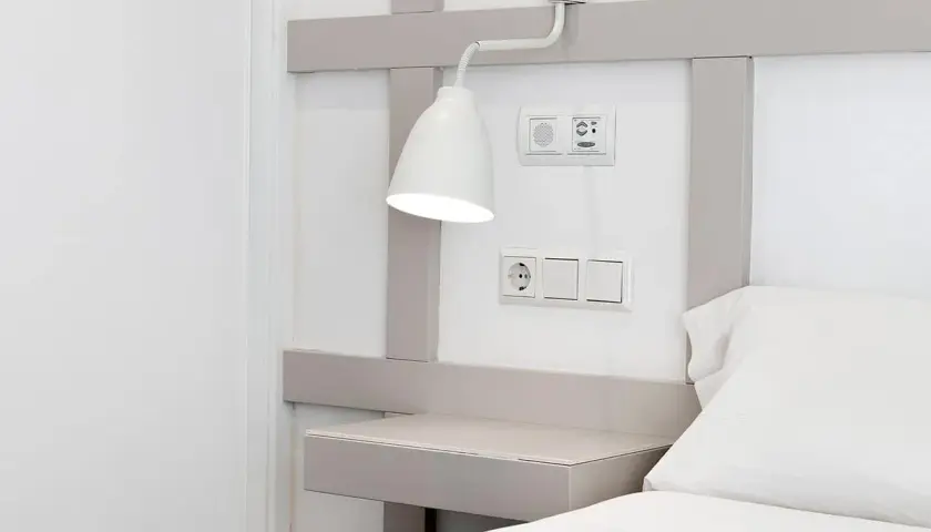 Interruptores y enchufe cerca del cabecero de la cama, con una lámpara orientable. La distancia entre interruptores cabecero cama es ideal para el control de luces.