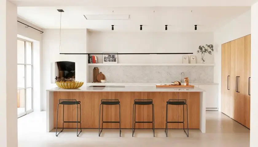 Cocina moderna con isla de madera y taburetes. Un proyecto de restaurar muebles de cocina podría dar vida a este espacio.