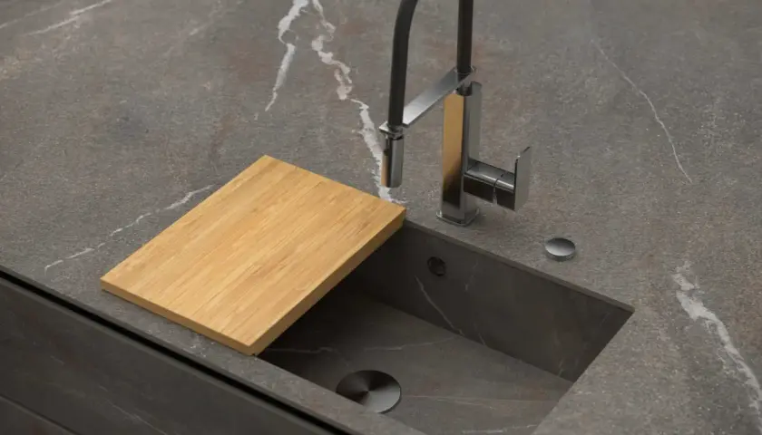 Encimera de cocina moderna con fregadero integrado, grifo flexible y tabla de cortar de bambú. Explora los tipos de fregaderos.