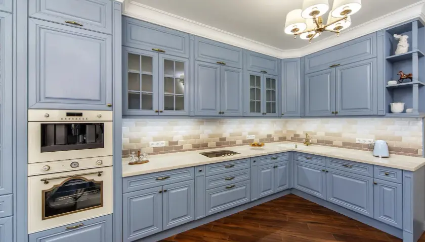 Cocina moderna con muebles de cocina pintados en azul pálido, encimeras claras y electrodomésticos integrados.