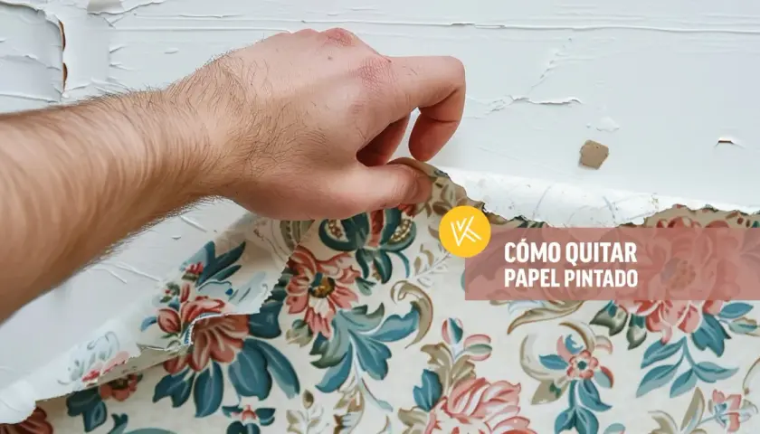 Mano retirando papel pintado floral de una pared blanca.