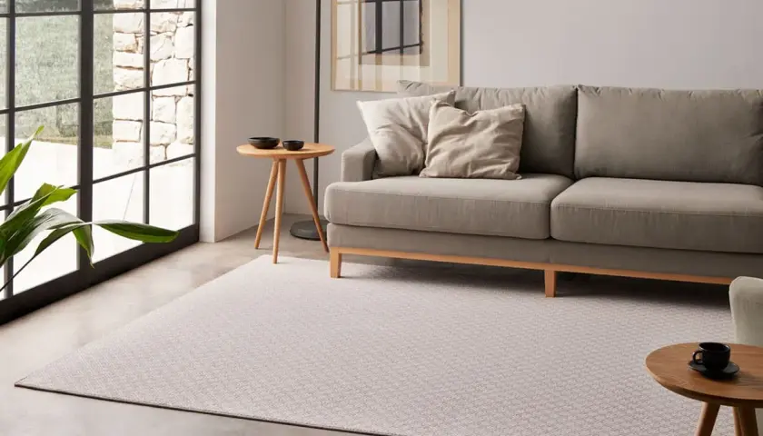 Sofá gris y alfombra de diseño geométrico, mostrando diferentes tipos de alfombras para un salón moderno.