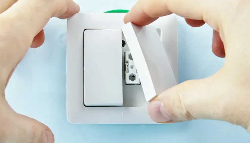 Manos instalan tapa en un interruptor doble Simon.