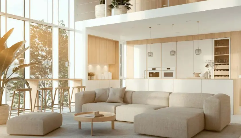 Salón con sofá modular beige, mesa de centro redonda y taburetes altos. Cocina blanca minimalista. Decoración Japandi con plantas y luz natural.