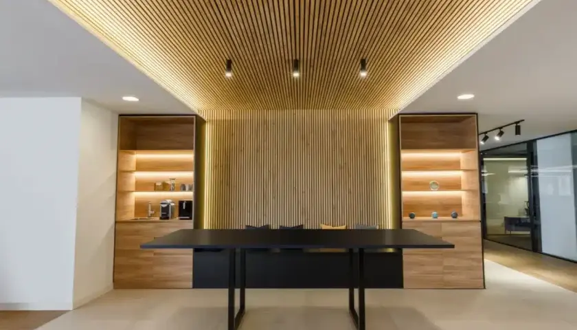 Revestimiento de pared de madera con iluminación cálida, estanterías y mesa de oficina moderna.
