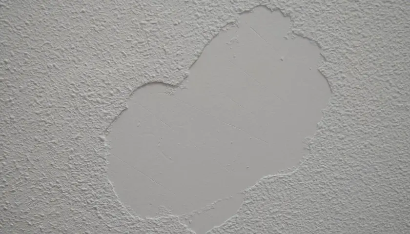 Detalle de paredes con gotele, mostrando una zona reparada con textura lisa sobre la rugosidad original.