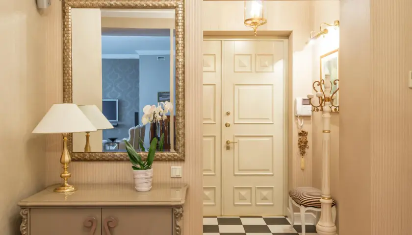 Ideas para pasillos estrechos como decorar: espejo dorado, consola, lámpara, orquídeas y suelo de damero.