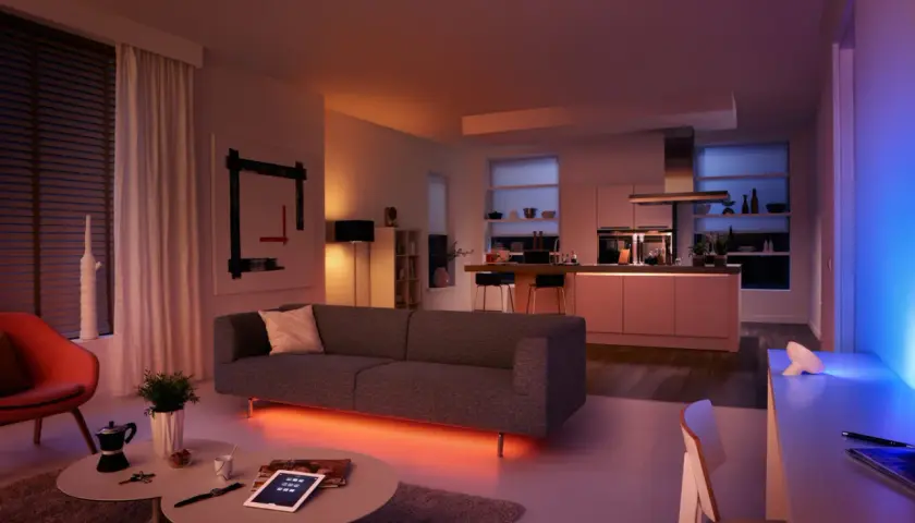 Salón y cocina modernos con iluminación ambiental. El color de la luz led cambia de naranja cálido a azul vibrante, creando una atmósfera acogedora.