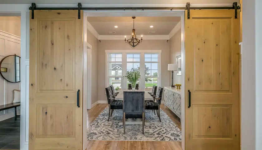 Dos puertas corredizas de madera rústica flanquean un comedor elegante, mostrando diferentes tipos de puertas.