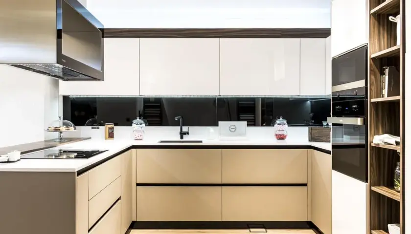 Cocina moderna con gabinetes blancos y beige, encimera blanca, campana extractora de acero inoxidable. Ideas para como diseñar una cocina funcional y elegante.