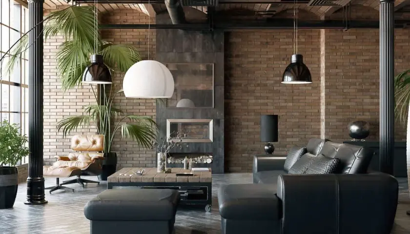 Sofá de cuero negro y sillón de cuero marrón junto a paredes estilo industrial de ladrillo visto. Chimenea y plantas verdes completan el ambiente.