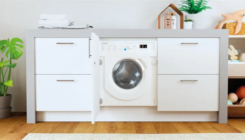Lavadora Indesit con puerta abierta, lista para el lavado. El desague lavadora está oculto tras el mueble.