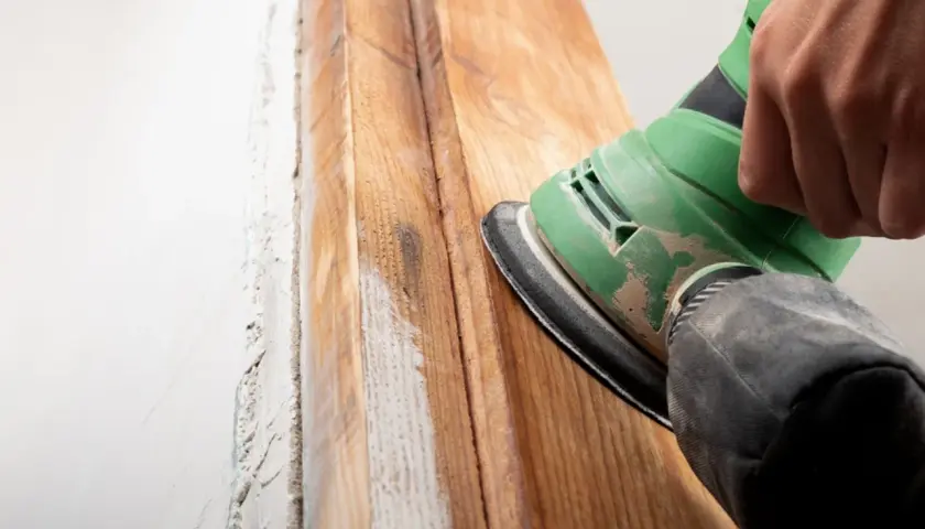 Mano lijando madera para quitar barniz. El proceso revela la veta natural.