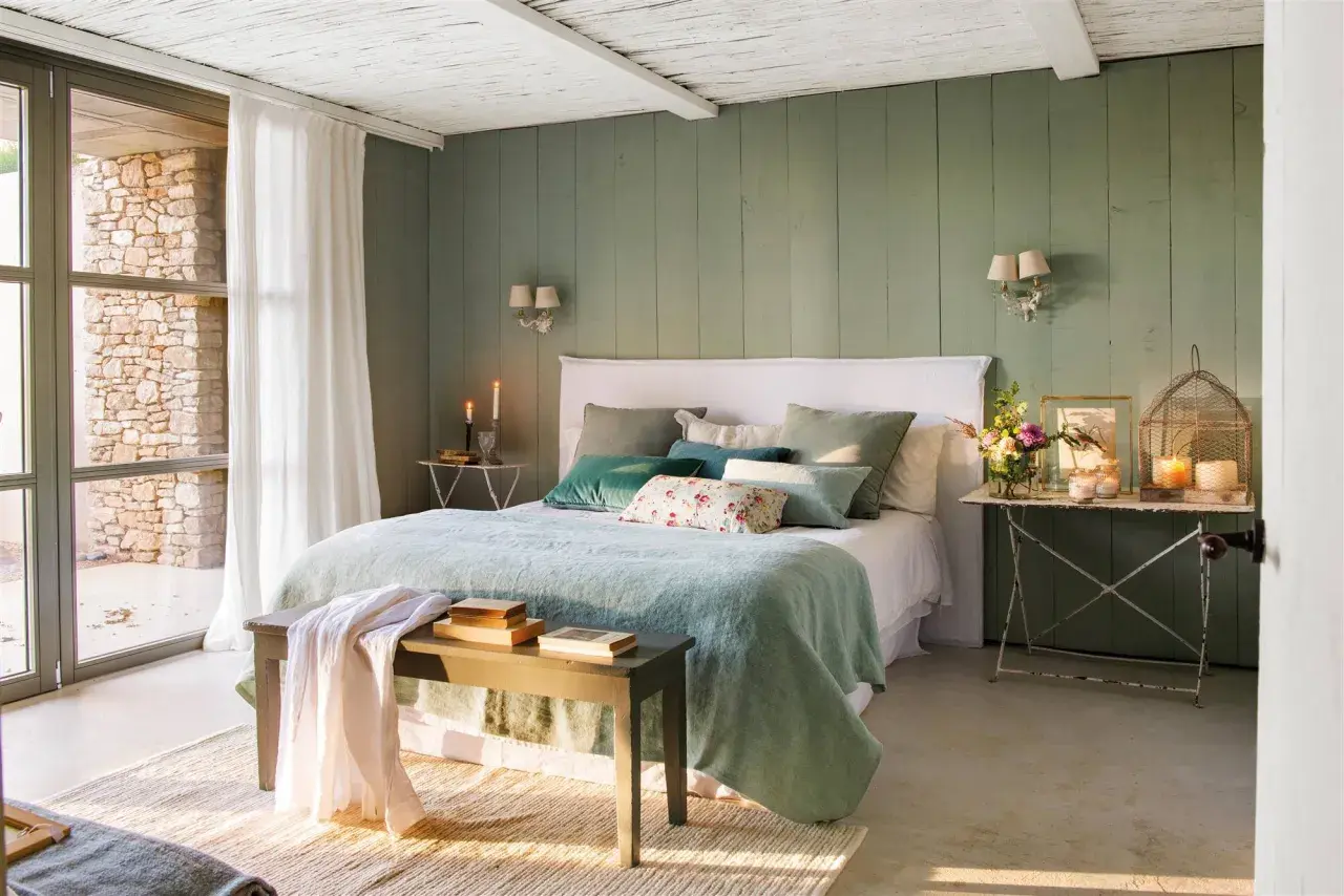 Habitación con paredes verde menta, cama con ropa de cama azul claro y cojines verdes. Inspiración de colores para habitaciones.