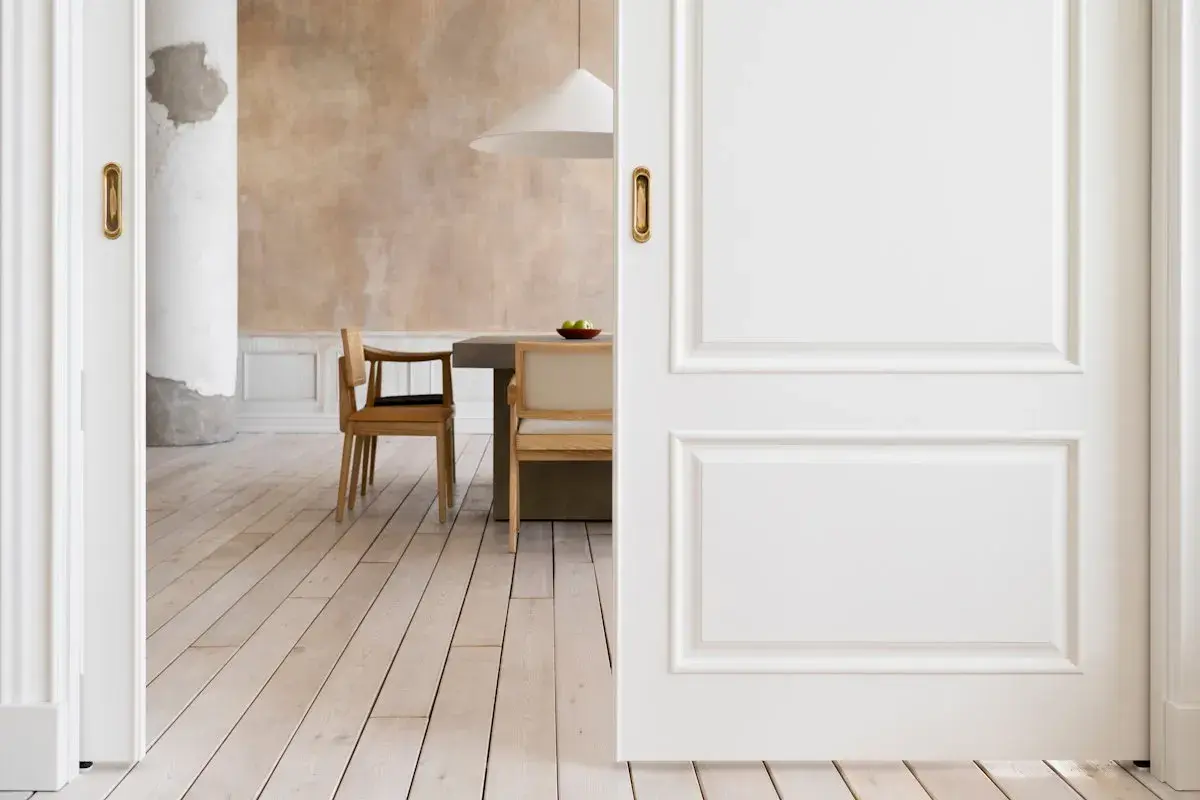 Puertas blancas y suelo de madera clara crean un ambiente acogedor. El diseño busca combinar suelo y puertas para una estética armoniosa.