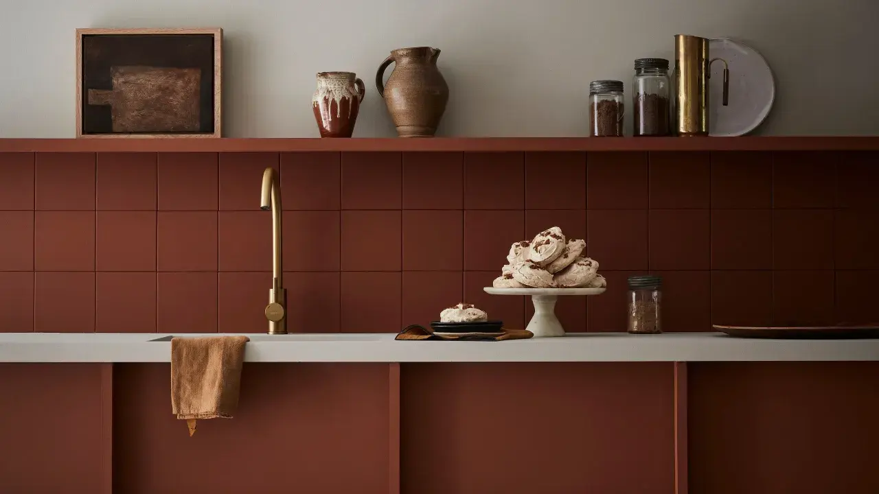 Encimera de cocina pintada en tono terracota, con grifería dorada y detalles decorativos.