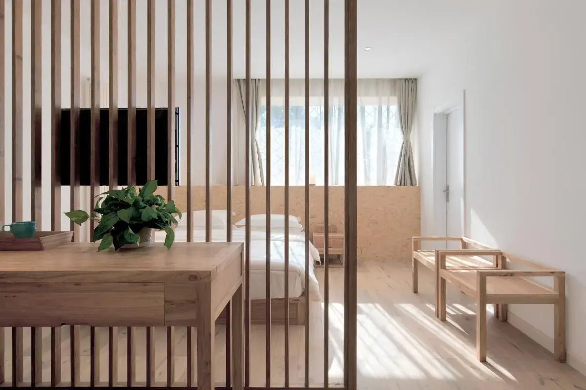 Elegante solución para separar ambientes sin obras, con un biombo de lamas de madera que delimita un dormitorio acogedor.