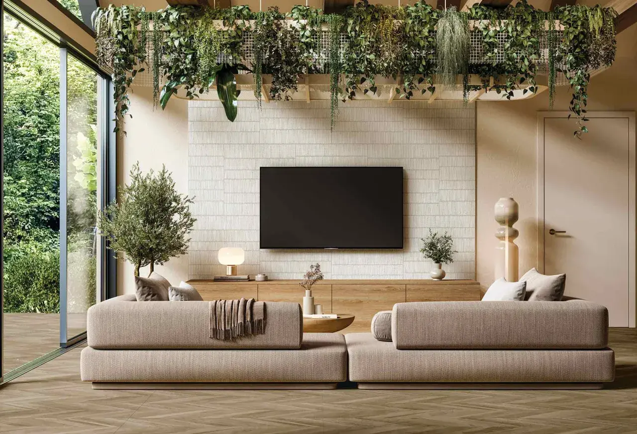 Un salón moderno con sofás beige, una pared con textura y plantas colgantes, reflejando las últimas tendencias en decoración de paredes.