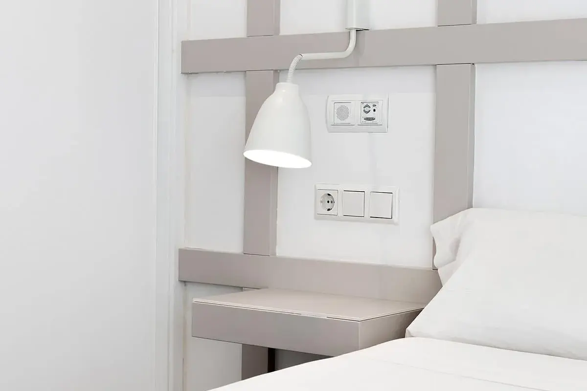 Interruptores y enchufe cerca del cabecero de la cama, con una lámpara orientable. La distancia entre interruptores cabecero cama es ideal para el control de luces.
