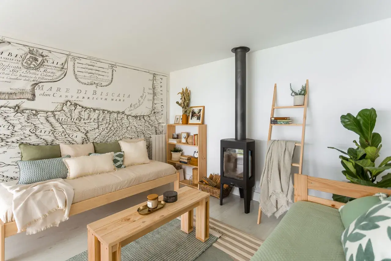 Acogedora sala de estar pequeña sencilla con sofá de madera, chimenea, estantería y un mapa antiguo en la pared.