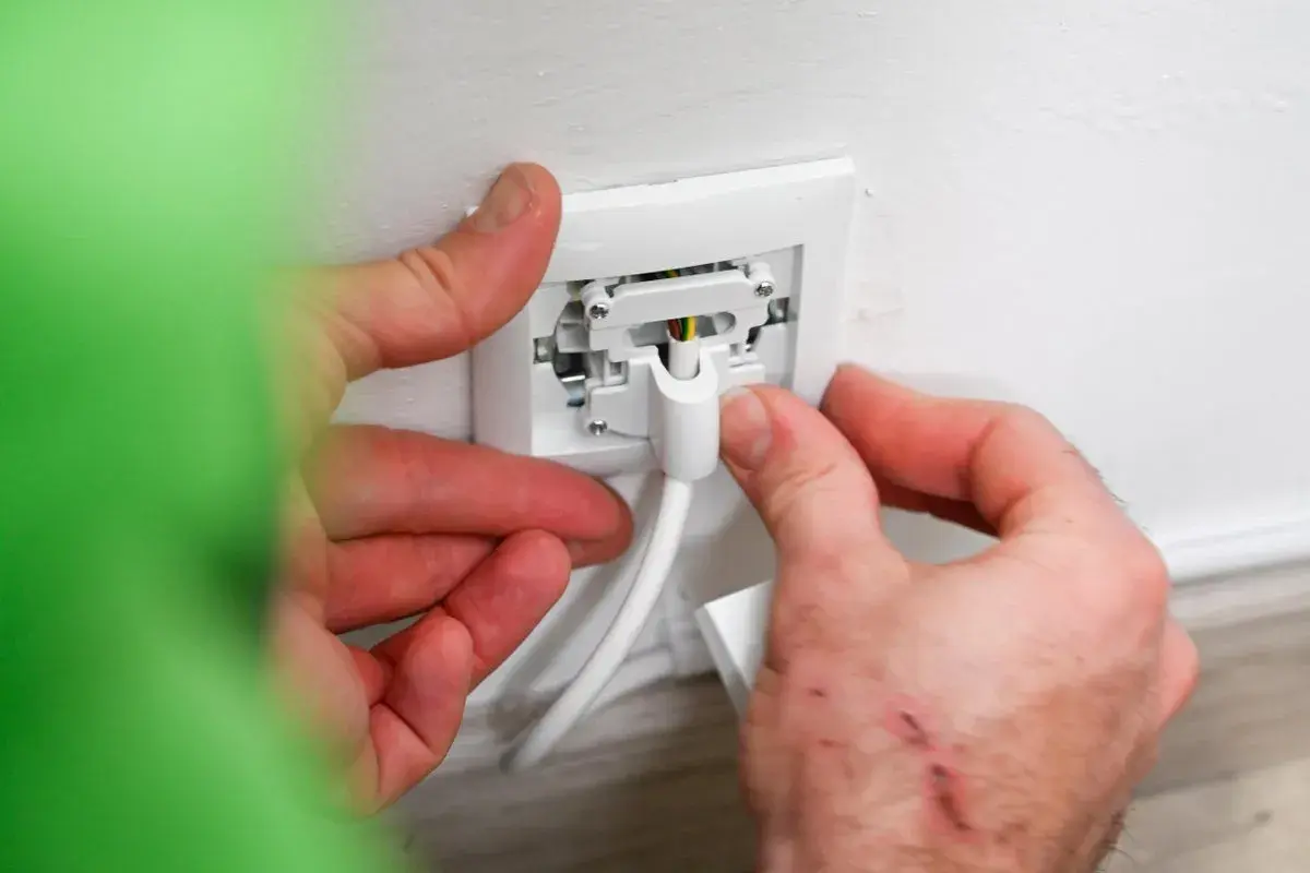 Manos conectando un cable a un enchufe para instalar enchufe de superficie.