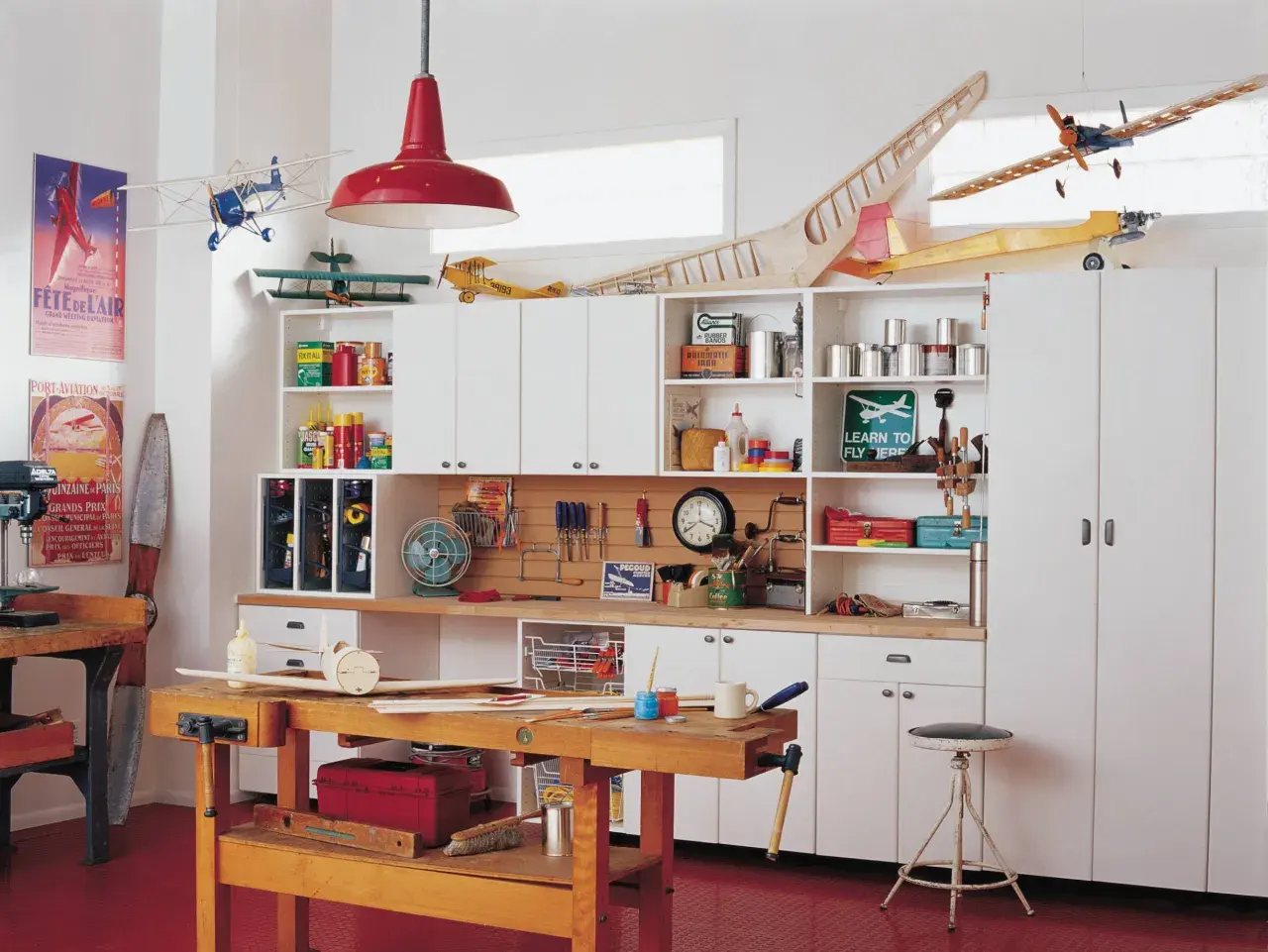 Un taller de bricolaje doméstico con maquetas de aviones, herramientas y estanterías llenas de materiales.