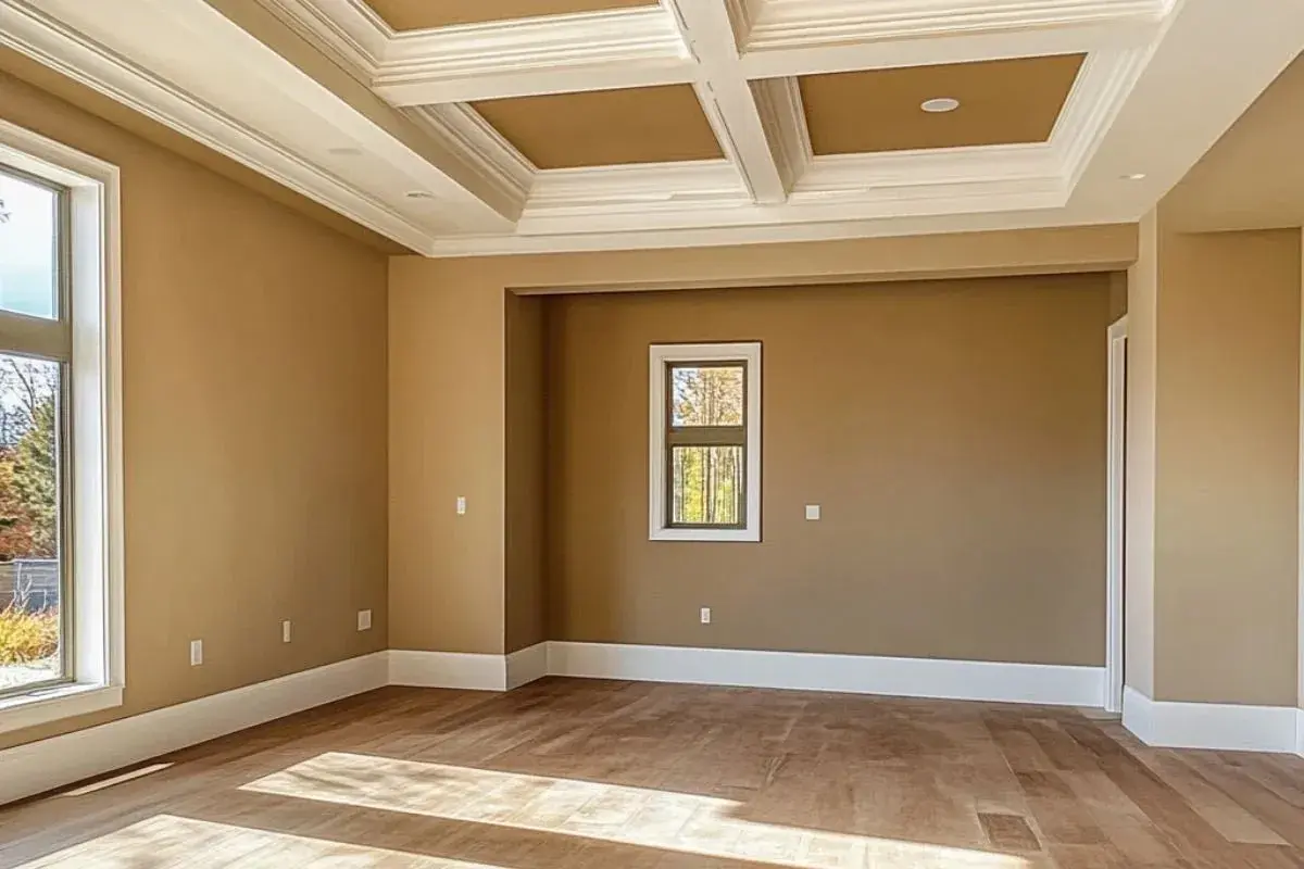 Habitación vacía con paredes color caramelo, techo artesonado blanco y suelo de madera. Ideal para empezar a pensar como pintar una habitacion.