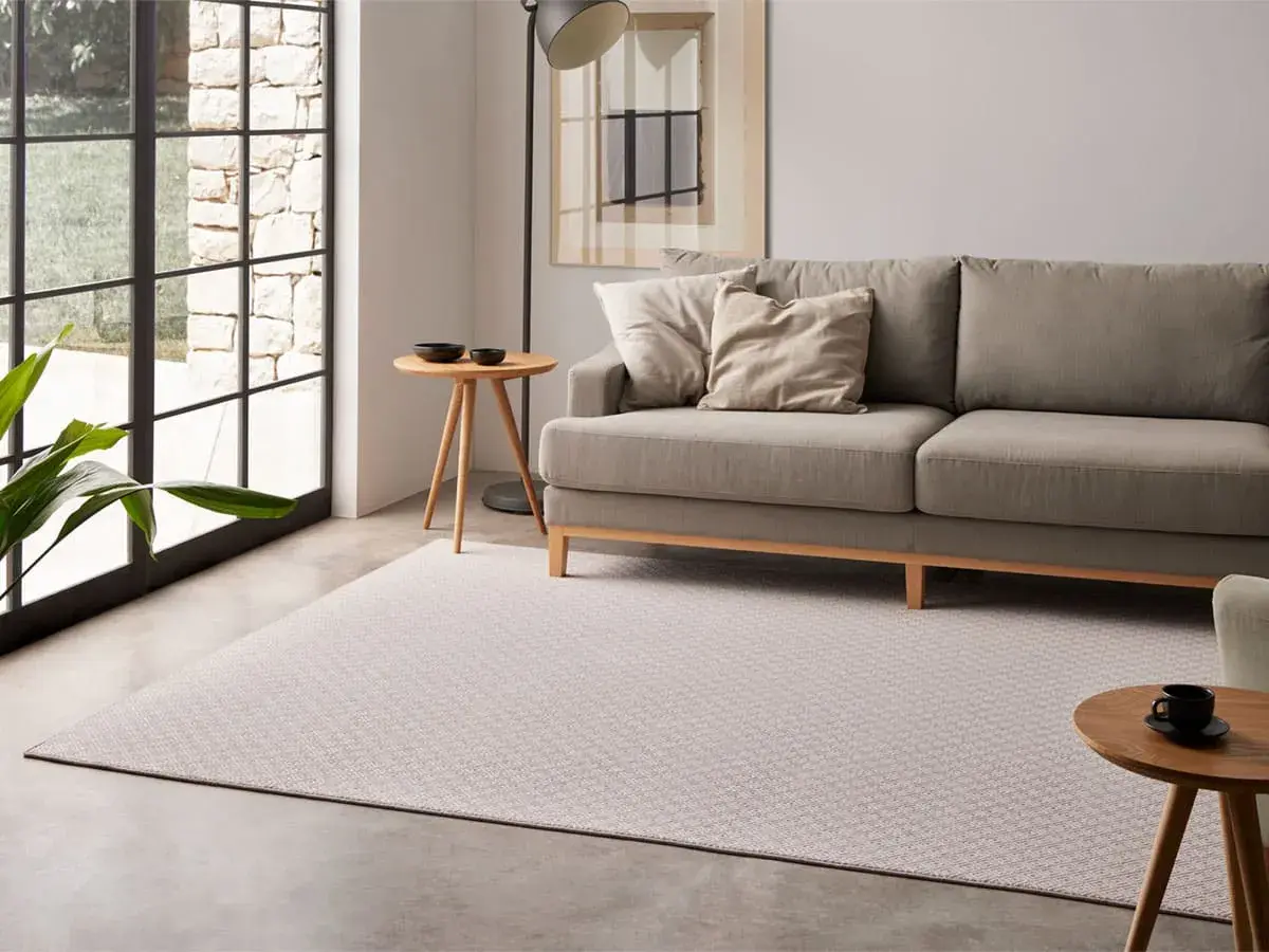 Sofá gris y alfombra de diseño geométrico, mostrando diferentes tipos de alfombras para un salón moderno.