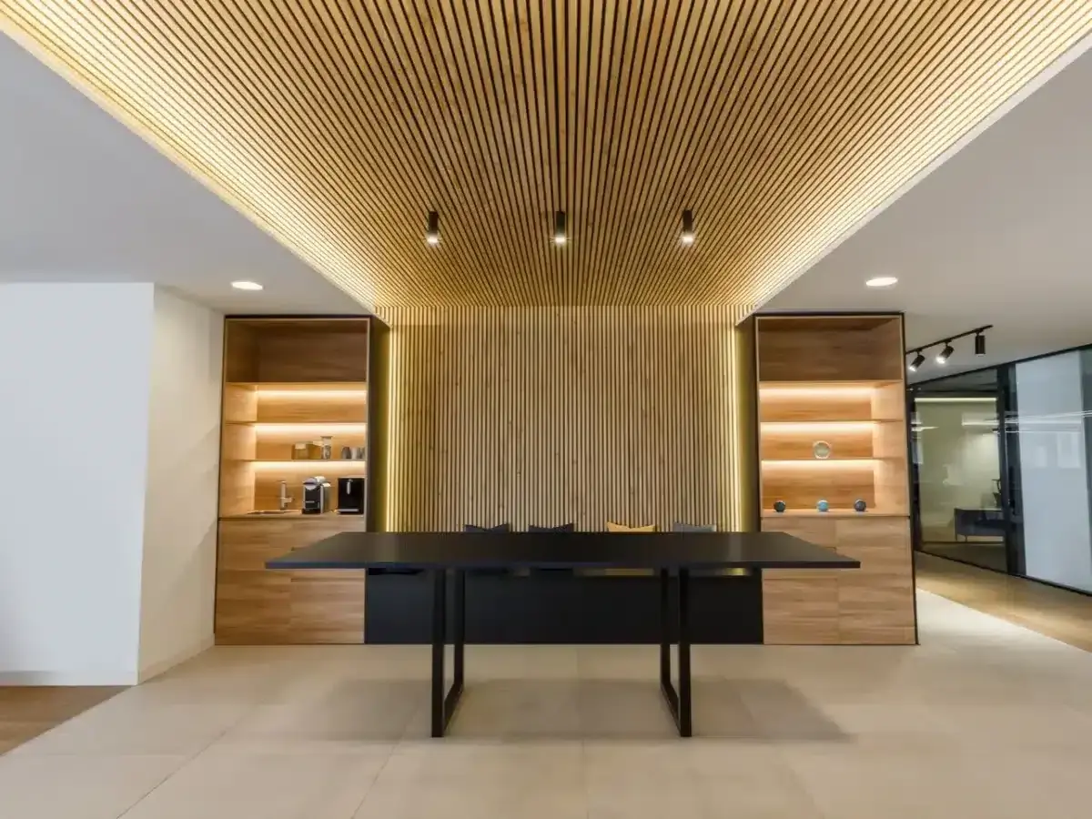 Revestimiento de pared de madera con iluminación cálida, estanterías y mesa de oficina moderna.