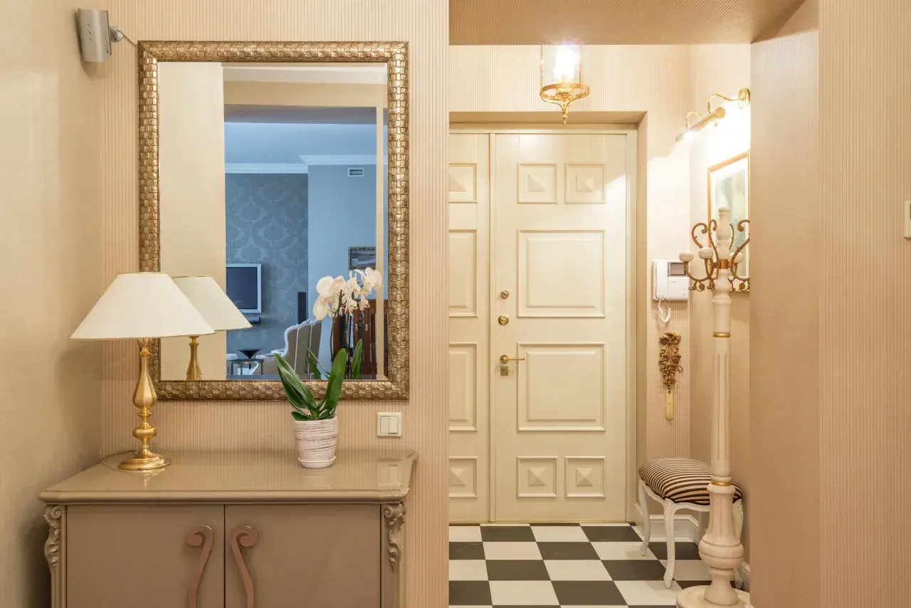 Ideas para pasillos estrechos como decorar: espejo dorado, consola, lámpara, orquídeas y suelo de damero.