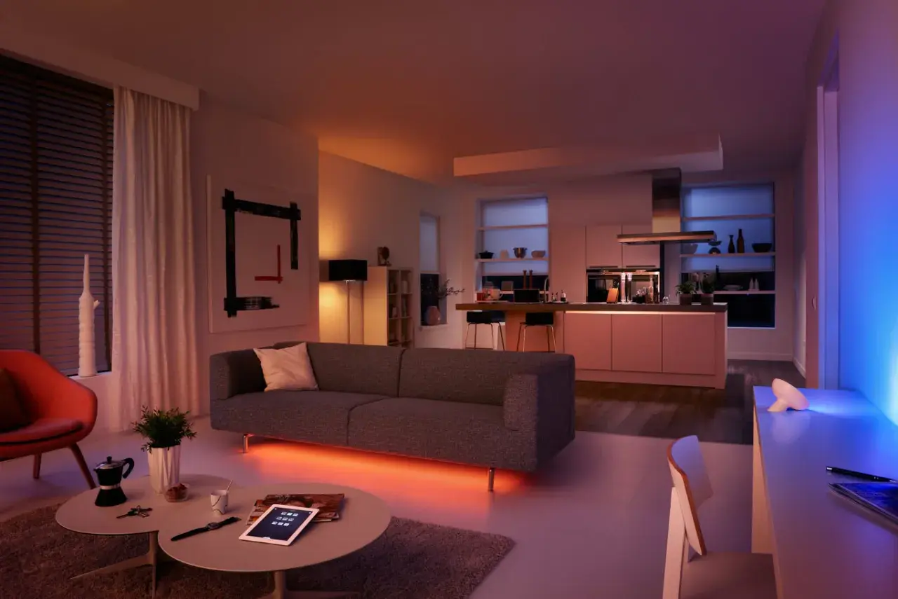 Salón y cocina modernos con iluminación ambiental. El color de la luz led cambia de naranja cálido a azul vibrante, creando una atmósfera acogedora.