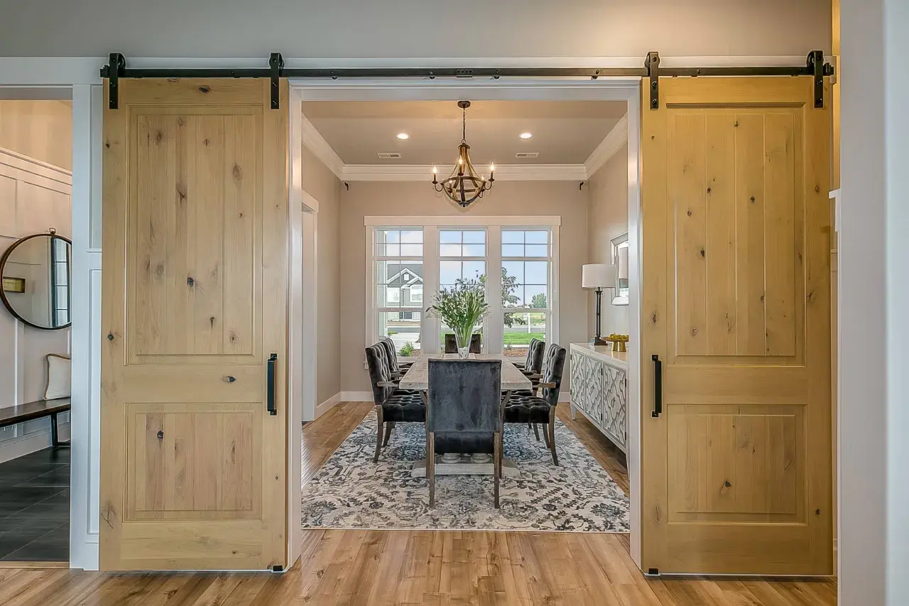 Dos puertas corredizas de madera rústica flanquean un comedor elegante, mostrando diferentes tipos de puertas.