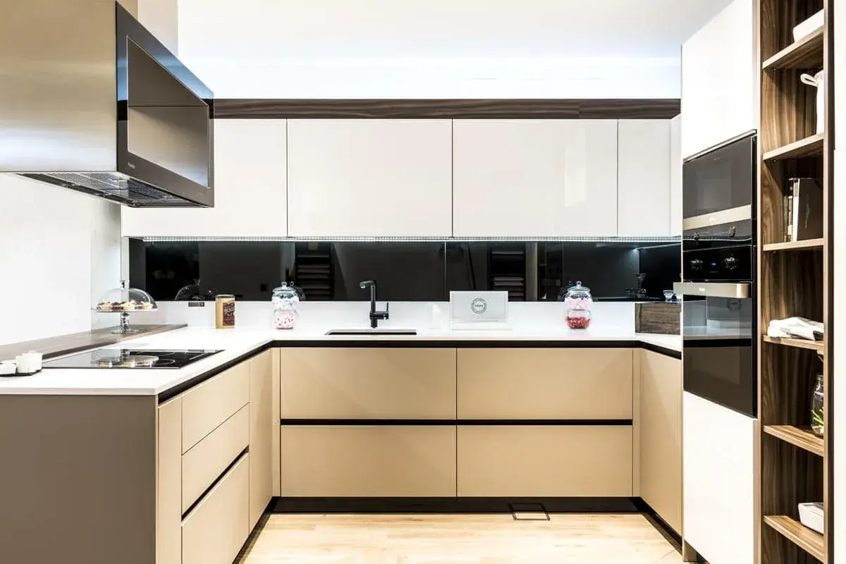 Cocina moderna con gabinetes blancos y beige, encimera blanca, campana extractora de acero inoxidable. Ideas para como diseñar una cocina funcional y elegante.