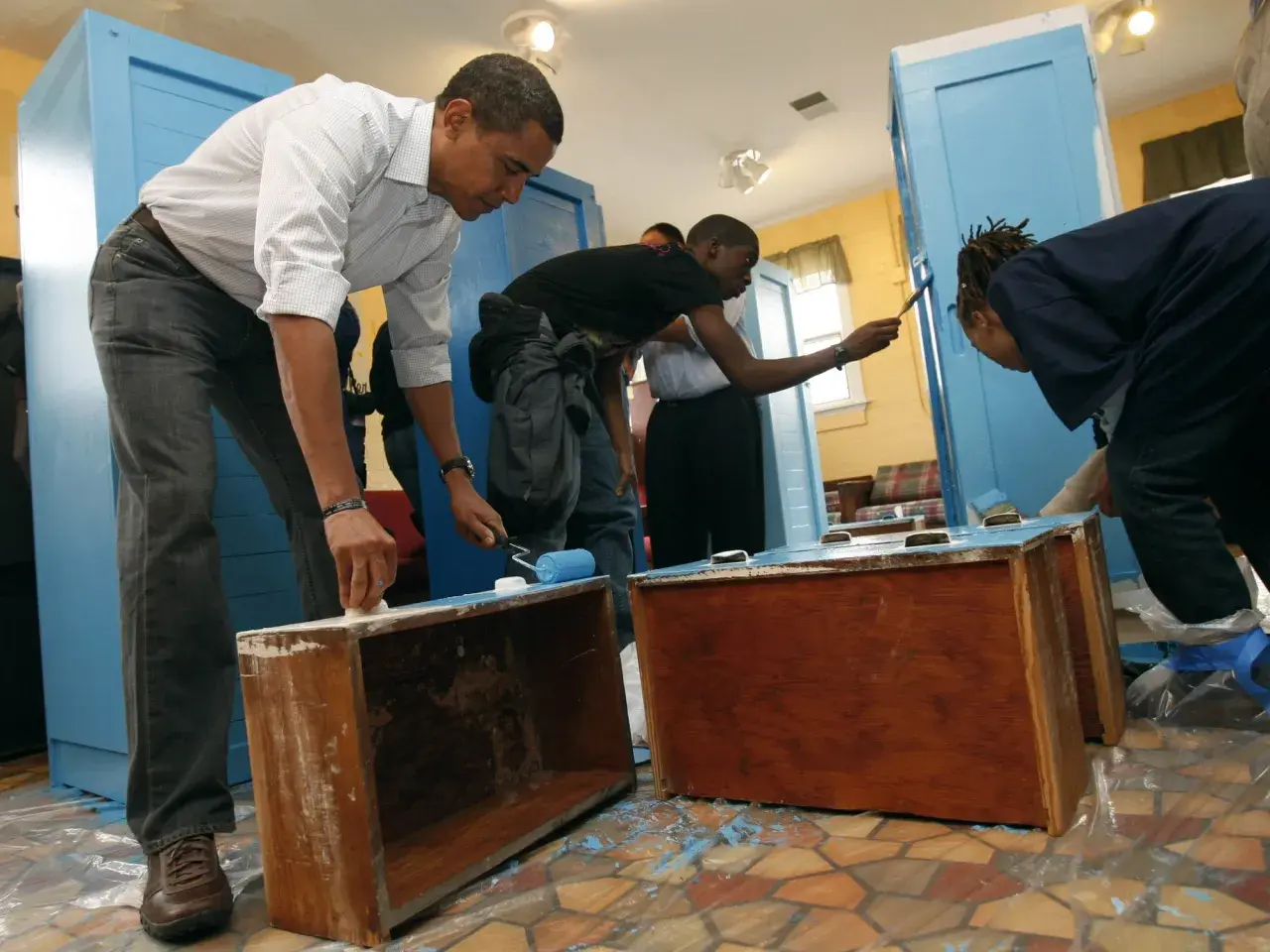Barack Obama y jóvenes pintan muebles de melamina de azul.