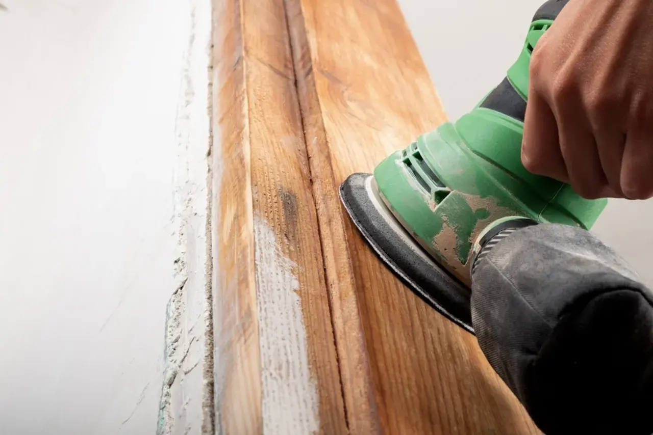 Mano lijando madera para quitar barniz. El proceso revela la veta natural.