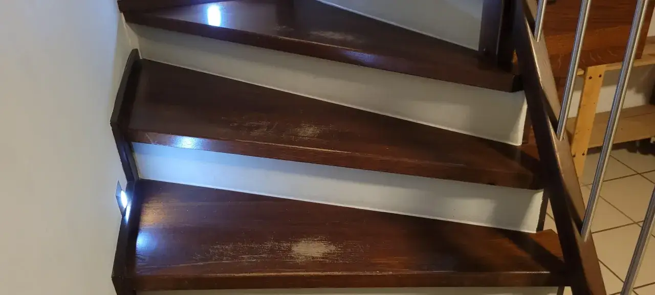 Escalera de madera oscura con marcas de uso. Se planea pintar escalera de madera sin lijar para renovarla.