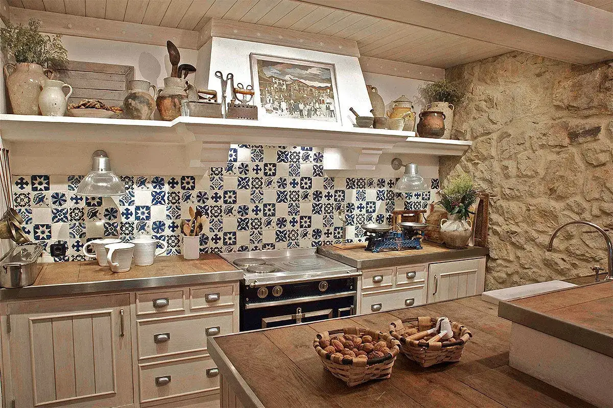 Encantadora cocina r&uacute;stica con azulejos azules y blancos, encimeras de madera y piedra, y detalles vintage.