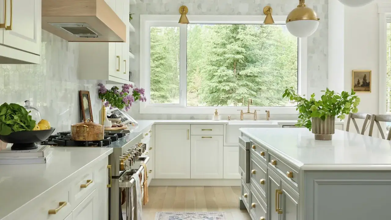 Cocina luminosa con isla central, encimeras de cuarzo y vista a un bosque. Ideas para como dise&ntilde;ar una cocina funcional y elegante.